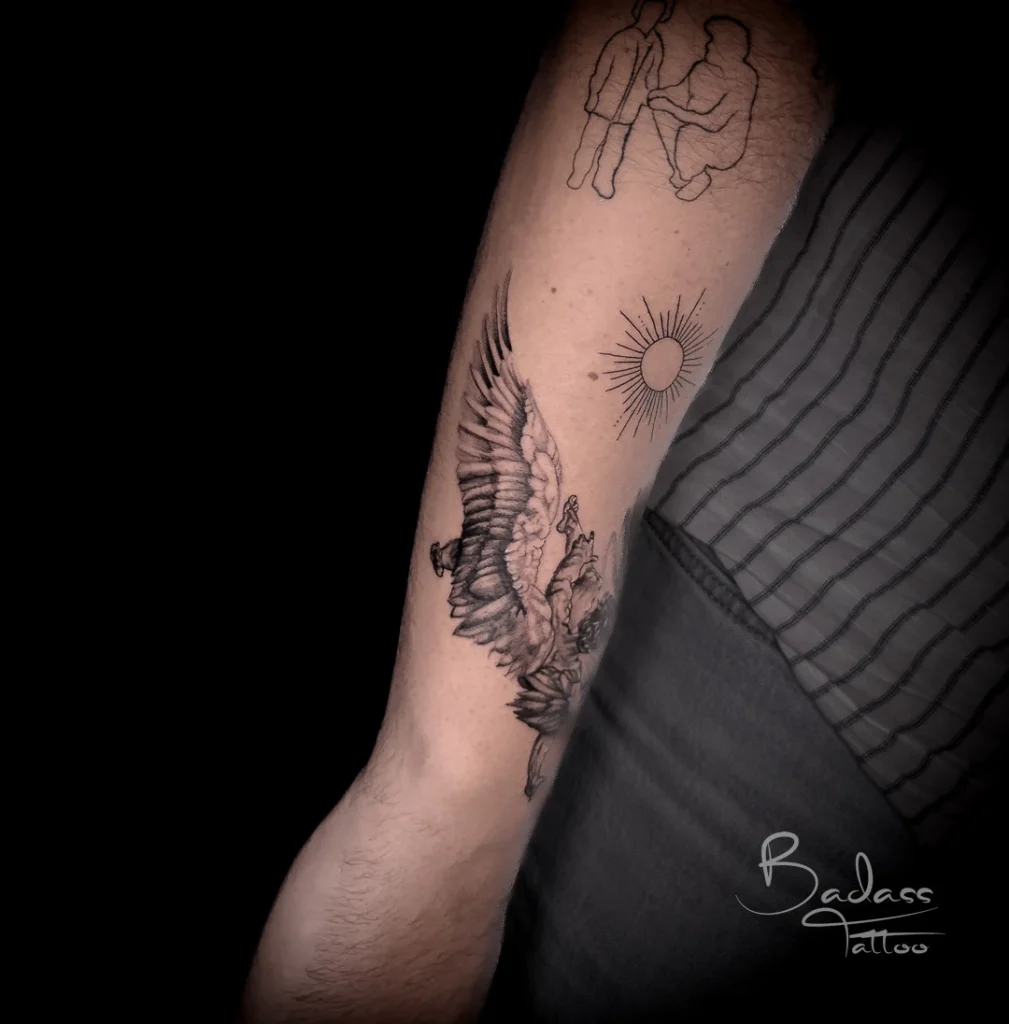 Tatuaj realizat de Cătălina — Personaj înaripat și soare pe braț