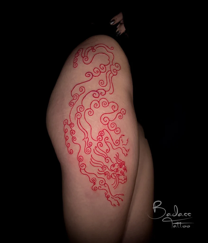 Tatuaj realizat de Cătălina — Dragon stilizat în linii roșii pe coapsă