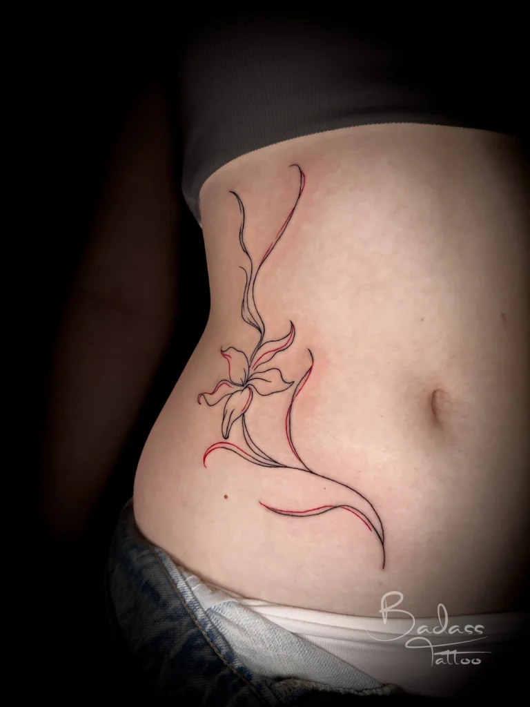 Tatuaj realizat de Cătălina — Floare în linii negre și roșii pe abdomen